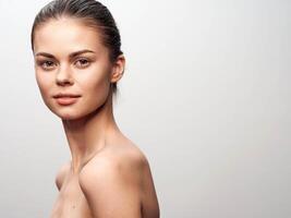 Portrait of a stunning young woman with flawless and smooth skin, standing gracefully against a photo