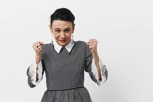 Happy woman in gray dress with hands on hips smiling at camera in bright studio setting photo