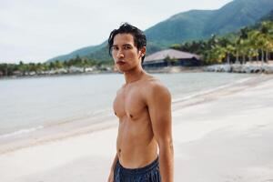 Smiling Asian Man Enjoying Tropical Beach Vacation with Muscular Torso photo