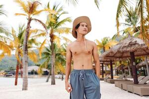 Smiling Asian Man on Tropical Beach Enjoying Summer Vacation photo