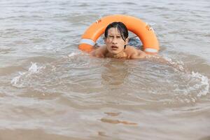 Alert Asian lifeguard using a red lifebuoy in the summer beach. the life saver of the sea. photo