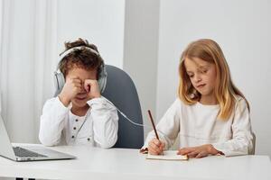 Happy Caucasian siblings studying together at home using laptops and headphones for online education photo