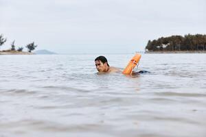 Guardian of Summer Joy. An Asian Lifeguard on a Beach, Rescuing Swimmers with a Lifebuoy in a photo
