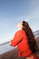 Joyful Smiles by the Sea. A Fun-Filled Summer Portrait of a Happy Woman Dancing in Red Clothes photo