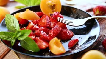 fresh fruit salad of ripe strawberries and apricots, on a light wooden table video