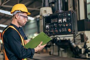 professional engineer working reading user manual control operate program CNC milling machine in heavy industry factory photo
