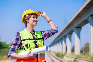 Portrait engineer women on railway tracks construction site with blueprint roll working project manager in suburb transportation line photo