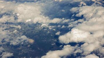 Aerial view of snow-capped mountains covered by scattered clouds. video