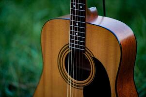 Acoustic guitar, orange string musical instrument placed in the area of trees and grass, playing music in the forest and relaxing. photo