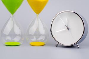 Hourglass on gray background, time and running out of time in studio photo style