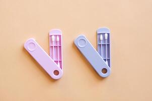Reusable silicone ear sticks in colored cases with a top view on a beige background. An alternative to disposable cotton swabs. Reduce costs and save money. photo
