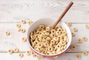 healthy cereal rings on a light wood background in a plate and scattered on the table. morning eat. Healthy children's breakfast. Dry muesli. photo
