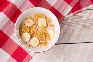 Healthy breakfast. Muesli with yogurt and banana on a light wooden background with a red tablecloth. View from above. Copy space. photo