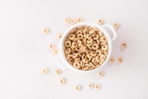 healthy cereal rings on a white background in a plate and scattered on the table. morning eat. Healthy children's breakfast. Dry muesli. top view photo