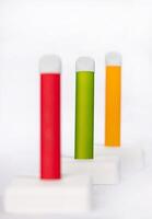 Set of colorful disposable electronic cigarettes on a display stand on a white background. The concept of modern smoking, vaping and nicotine. photo