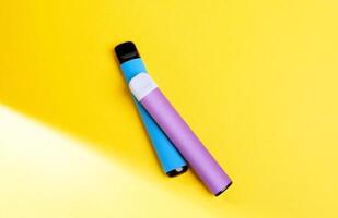 disposable electronic cigarettes with shadow on a yellow background with copy space. The concept of modern smoking, vaping and nicotine. top view. photo