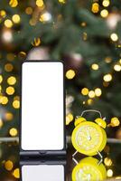 Phone with isolated screen and clock alarm on the background of the Christmas tree, bokeh and garland. New year gift, sales and offers. photo
