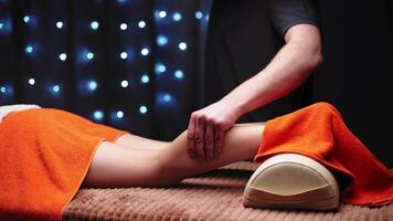 Shallow depth of field close-up of male hands massaging the ankle of a young woman in a professional massage room video