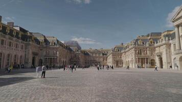 Versailles, France - March 19, 2024 - Tourists crowd the Royal Court at the Palace of Versailles with the palace's architecture and details as a background video