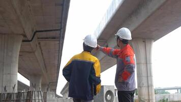 Back view of Asian male and female engineers Inspecting construction work radio command concrete road bridge highway video