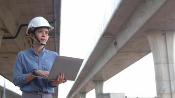 Asian female engineer uses laptop to inspect highway construction work video