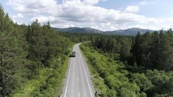 Top view of passing car on highway in forest. Scene. Beautiful view of country road with forest on sunny day. Trip out of town video