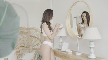 Frau steht beim Spiegel und nimmt Pflege von Sie selber. Aktion. sexy Frau führt aus Pflege im hell Innere. attraktiv gepflegt Frau gilt Sahne video