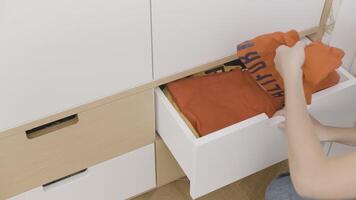 Order. Creative . A small white bedside table in which things, hoodies, etc. are stacked, it is opened and clothes are taken out. video
