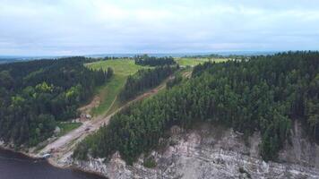 skön grön berg.klipp.på se från de Drönare. en stor kulle med stor gran träd runt om och en väg den där står på de flod. video