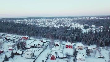 Top view of beautiful city with colorful houses in forest in winter. Clip. Town with cottages in wooded area in winter. Cozy winter town in middle of forest video