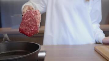 The cook picked up the raw meat with tongs and placed it on the pan. ACTION. A cook in a white tunic prepares meat. Man put a steak in a frying pan video