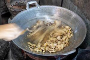 Close-up view of blurred motion of a female cook's hand holding a spatula to stir-fry pork. photo