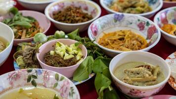Close-up view of sticky rice, curry, laab, stir-fry and many other dishes packed in bowls. photo