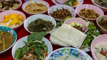 Close-up view of sticky rice, curry, laab, stir-fry and many other dishes packed in bowls. photo