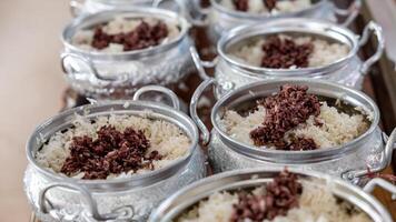 Close-up view of cooked rice packed in various aluminum pots. photo