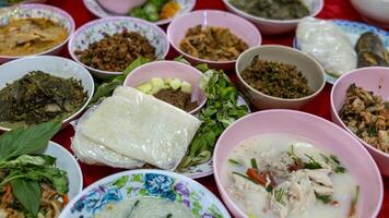 Close-up view of sticky rice, curry, laab, stir-fry and many other dishes packed in bowls. photo
