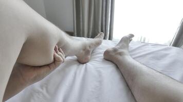 Leg massage to relax muscles and injuries. Close-up view of man using hands to massage his calves in bed in morning to relieve tight, numb and inflamed muscles. Concept of health care and treatment video