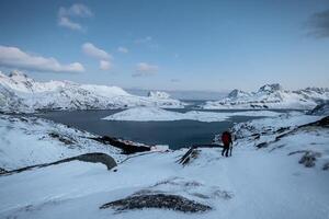 Climber lost on snowy mountain with sky on arctic ocean photo