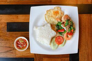 Stir-fried basil, chili with shrimp, squid with fried egg and white rice photo
