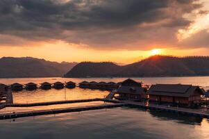 Sunset over mountain and raft resort in tropical rainforest on dam at Kanchanaburi photo