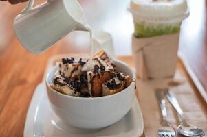 Pouring fresh milk on banana chocolate chip bread with ice honey tea photo