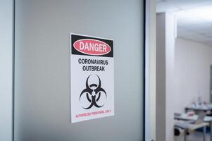 Alert notice on the door of danger coronavirus outbreak with biohazard symbol and authorized personnel only photo