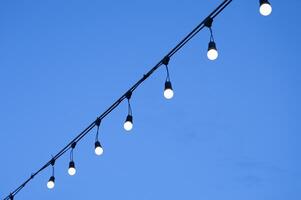 Row of illuminated light bulb hanging on string photo