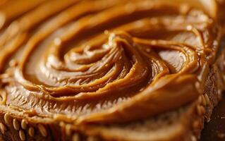 Closeup of smooth peanut butter spread on a slice of toast with sesame seeds photo