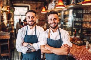 Portrait of two cheerful male chefs with arms crossed, standing in a modern restaurant photo