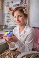 Ekaterinburg, Russia, February 14 2024 Cute girl at home solving a rubik's cube. It was invented by Hungarian architect Erno Rubik in 1974. photo