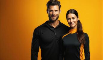 Confident athletic couple posing on orange background photo