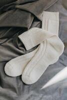 Hand knitted white socks on a grey background. Concept for handmade and hygge slow life. photo