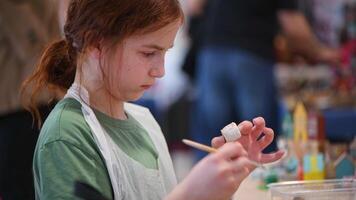 girl makes a wooden product with her own hands, paints it with white paint photo