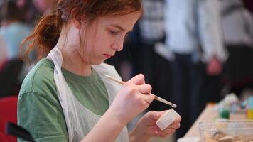 girl makes a wooden product with her own hands, paints it with white paint photo